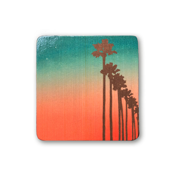 art block with palm tree silhouettes against ombre sunset sky
